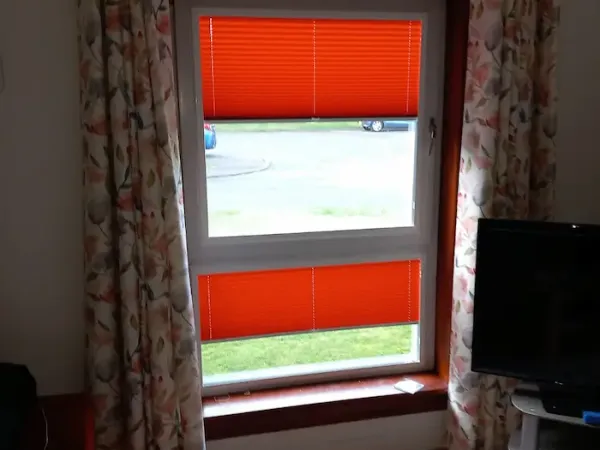 Orange pleated blinds paired with curtains