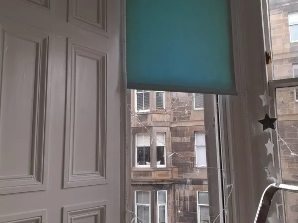 Teal roller blind in an Edinburgh tenement window