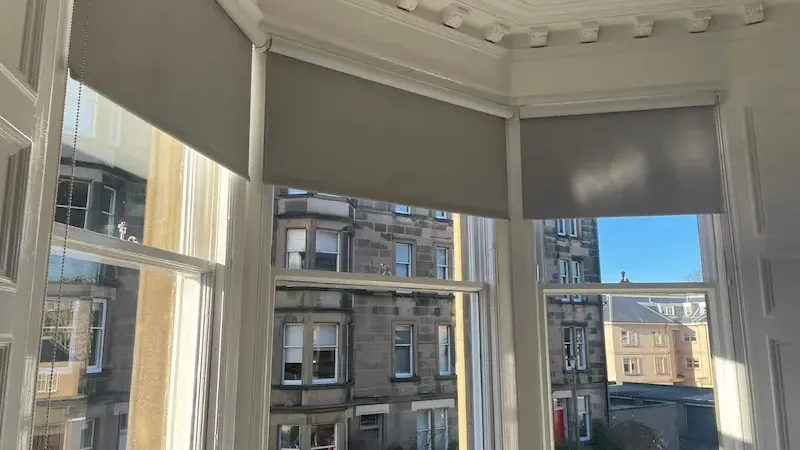 Made-to-measure roller blinds fitted across the bay window of an Edinburgh tenement flat